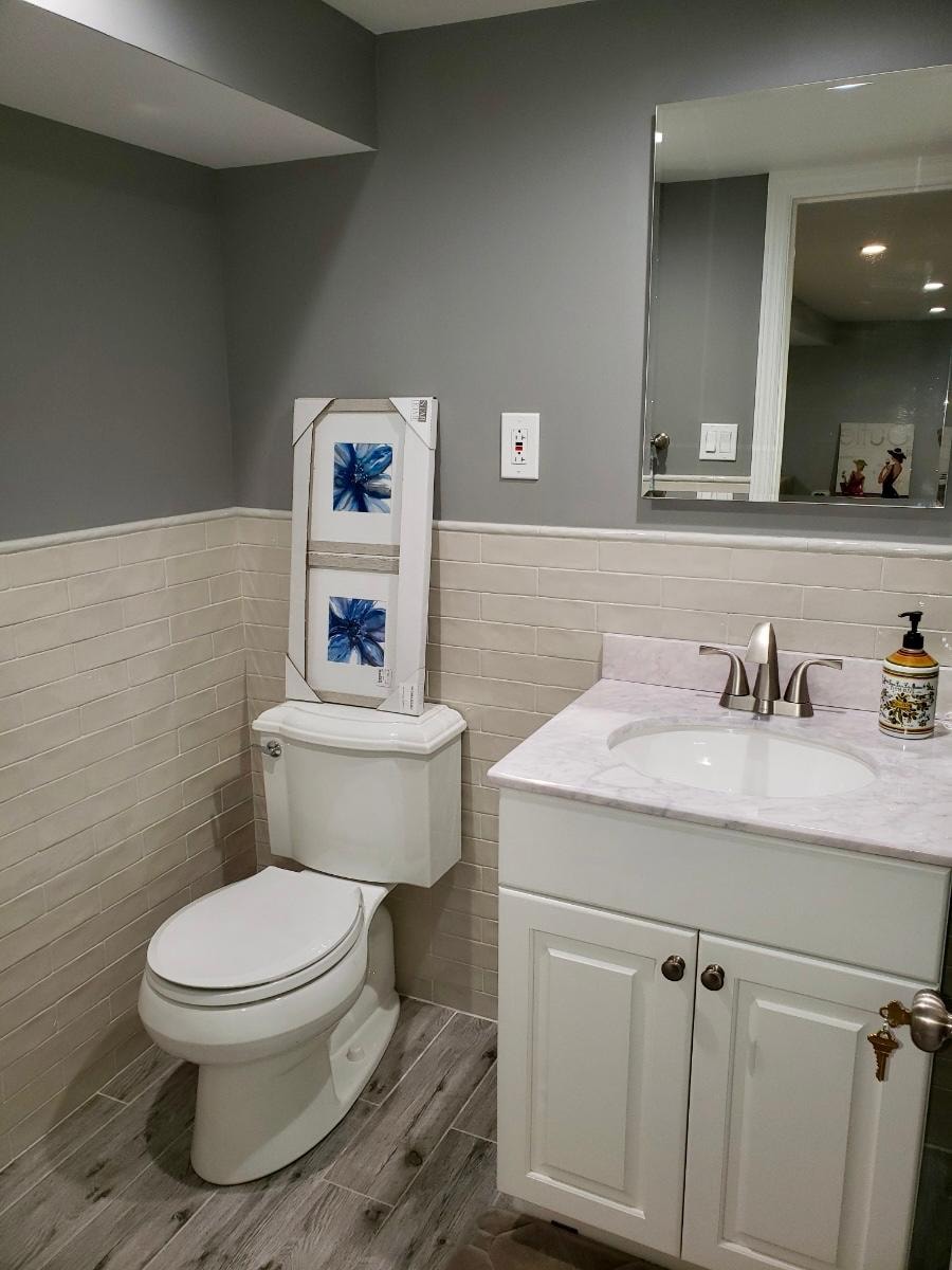Bathroom remodel — gray subway tile wainscoting, marble countertop vanity and wood-look tile floor