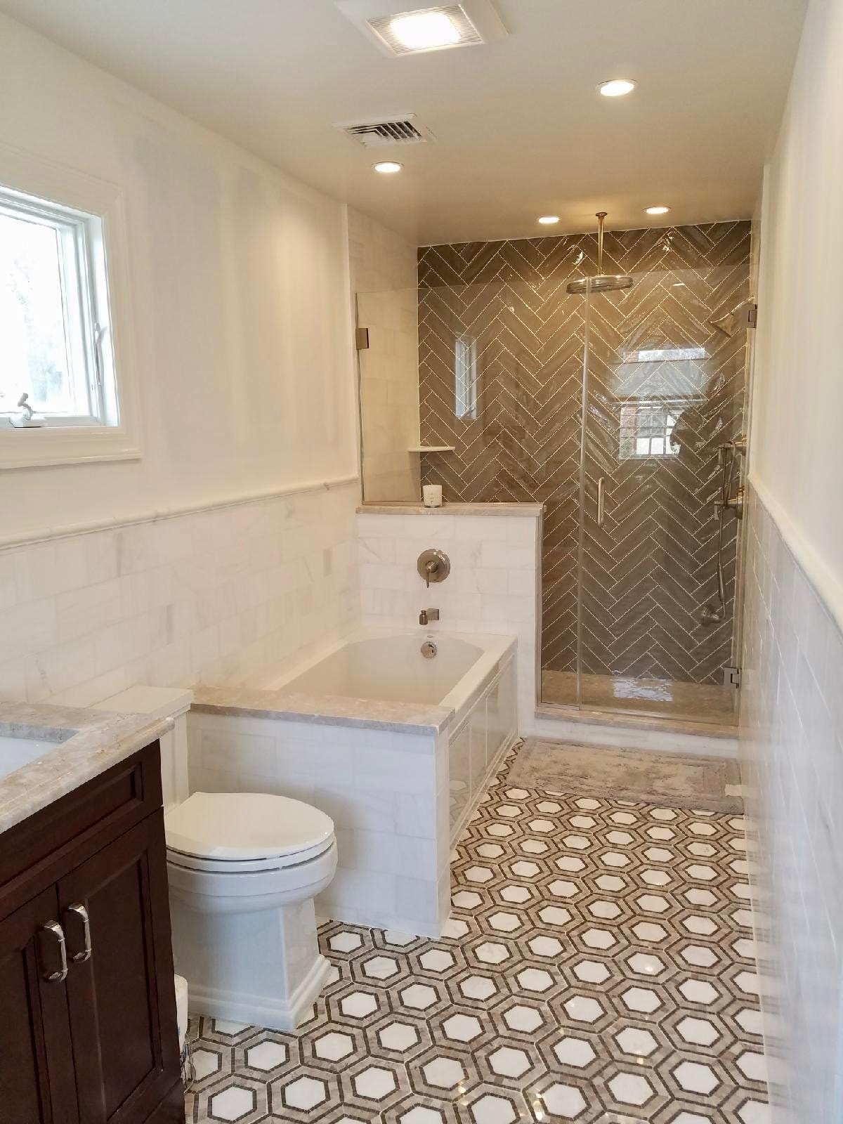 Bathroom remodel — herringbone tile shower surround, freestanding soaking tub and hexagon marble floor
