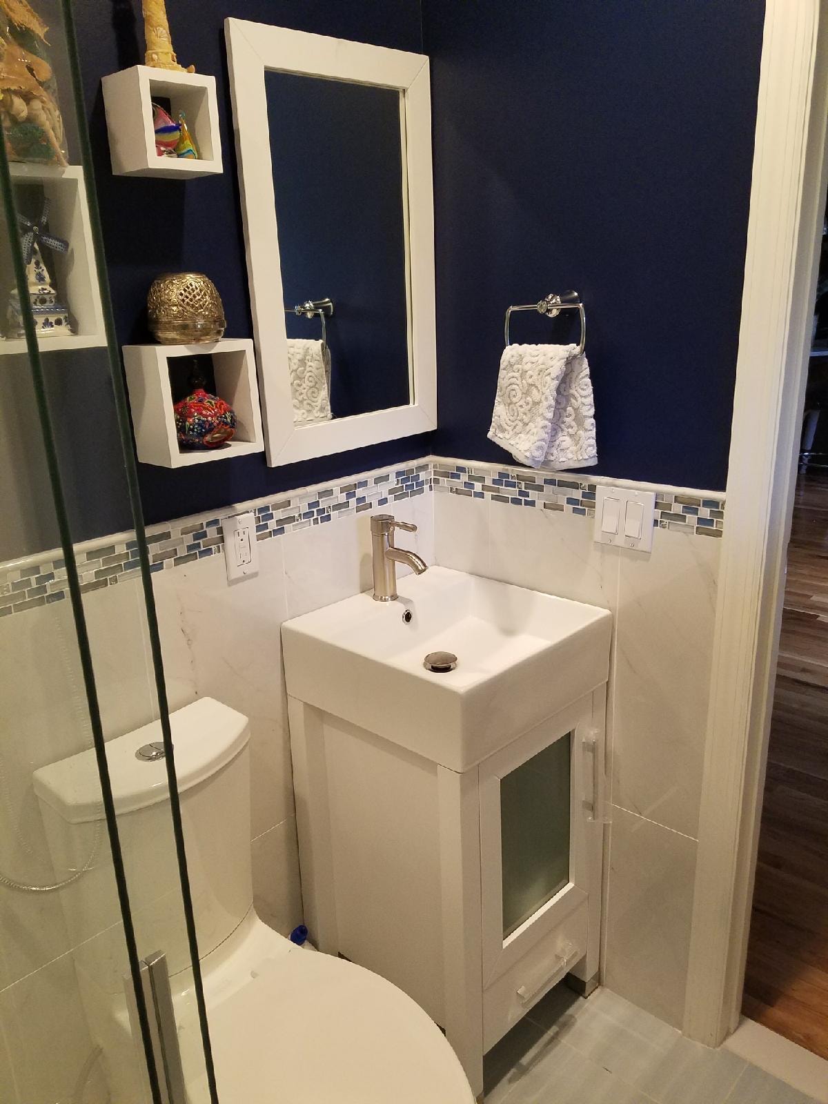 Bathroom remodel — navy accent wall, mosaic tile border, glass shower enclosure and modern vanity