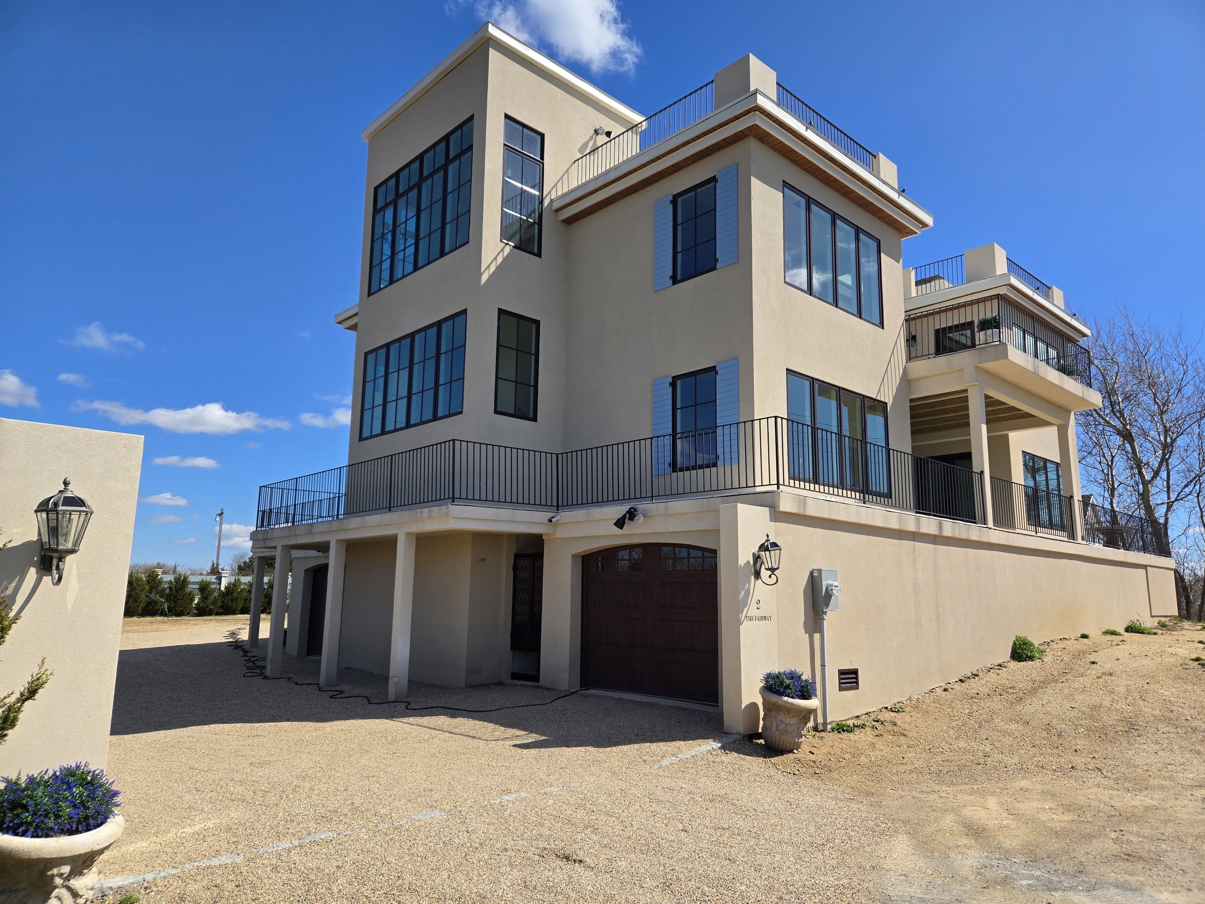 Full home build — Oak Beach: rear elevation with floor-to-ceiling steel windows, rooftop terrace and garage level