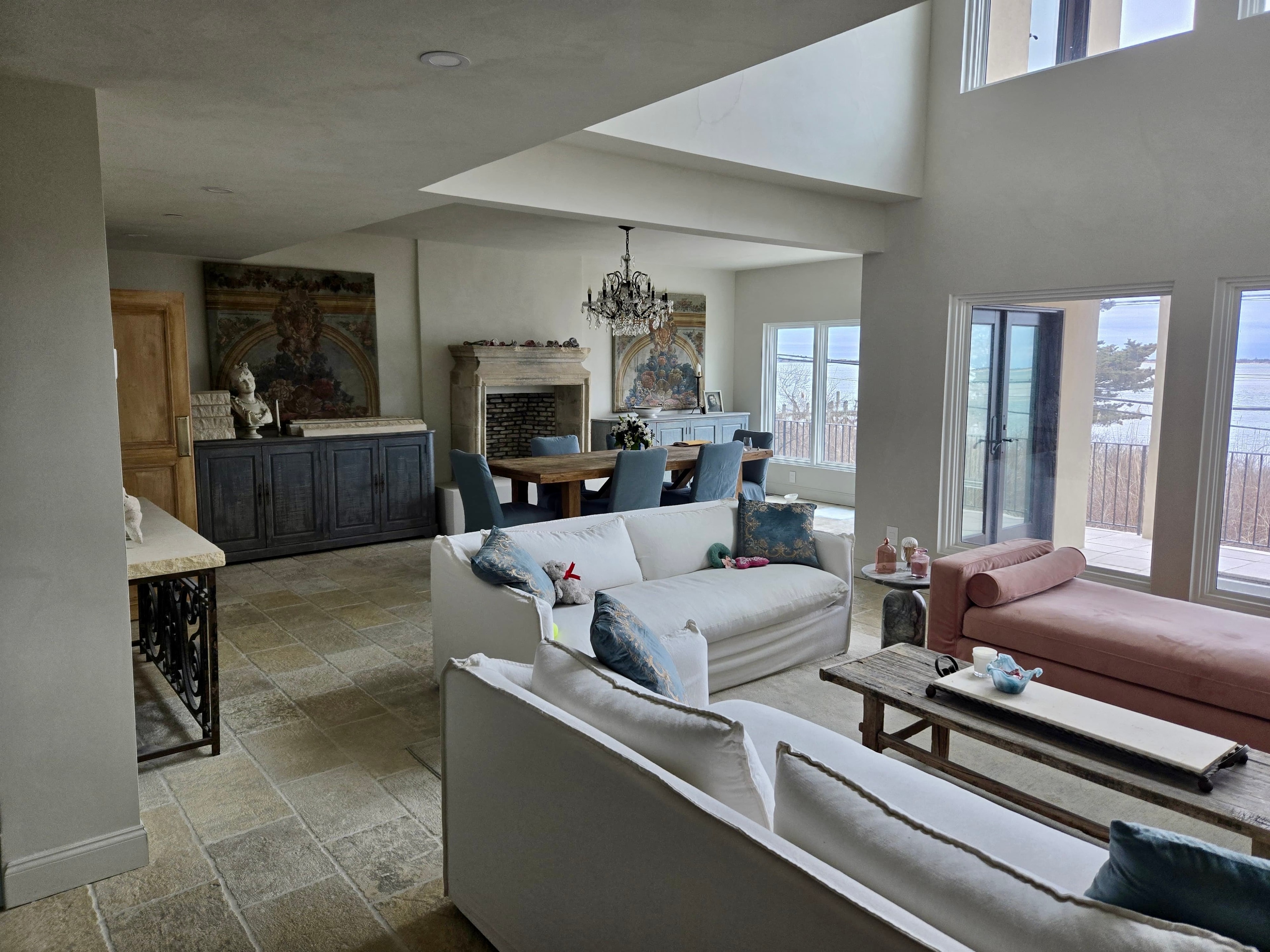 Full home build — Oak Beach: open-concept living and dining with stone fireplace, crystal chandelier and waterfront views