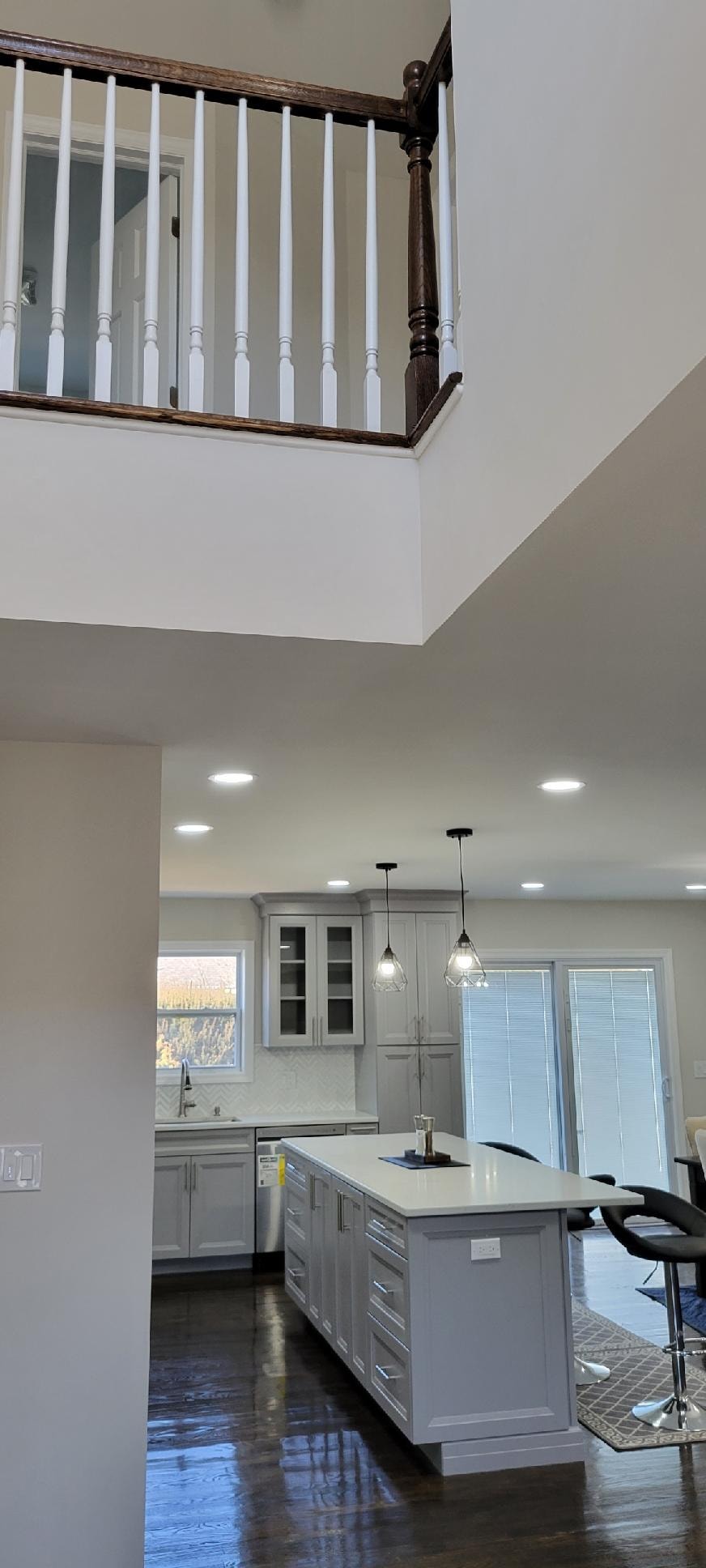 Open concept kitchen with gray cabinetry and mezzanine above