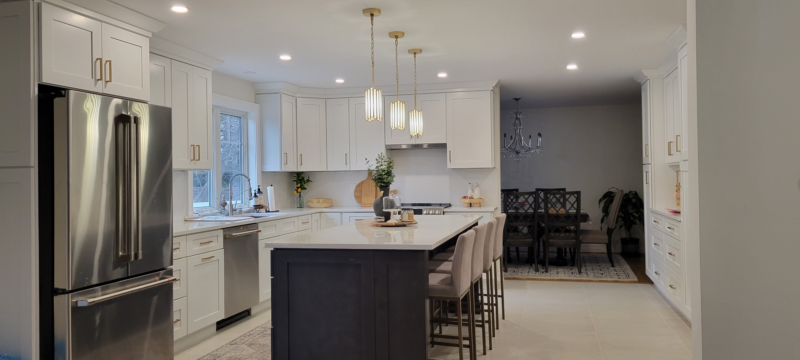 Kitchen renovation with white cabinetry, dark island and dining room view